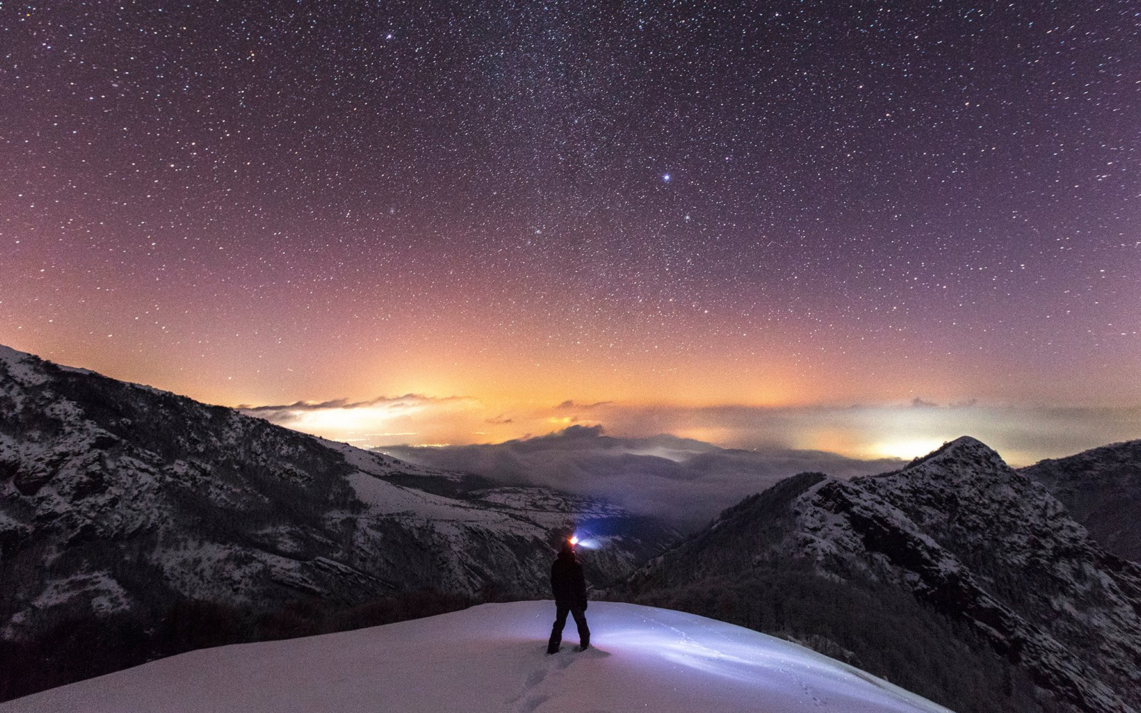 Person on mountain summit with night sky